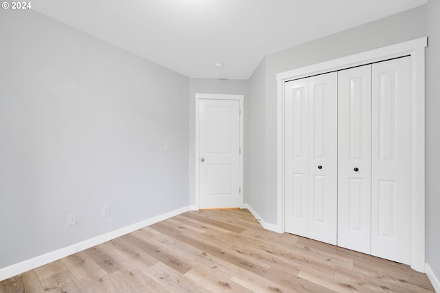 unfurnished bedroom with a closet and light wood-type flooring