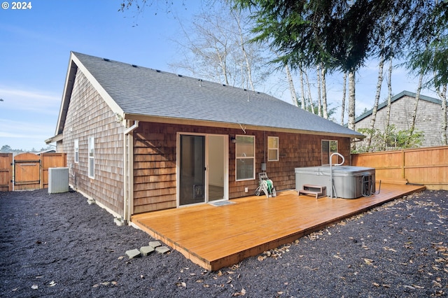 back of house with a hot tub, cooling unit, and a deck