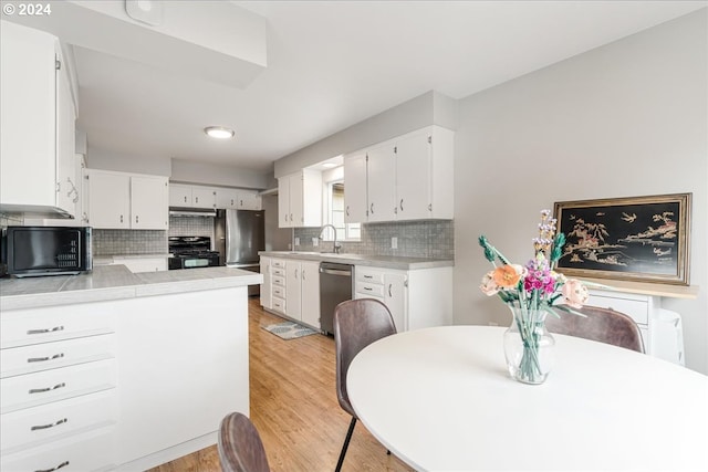 kitchen featuring white cabinetry, sink, kitchen peninsula, decorative backsplash, and black appliances