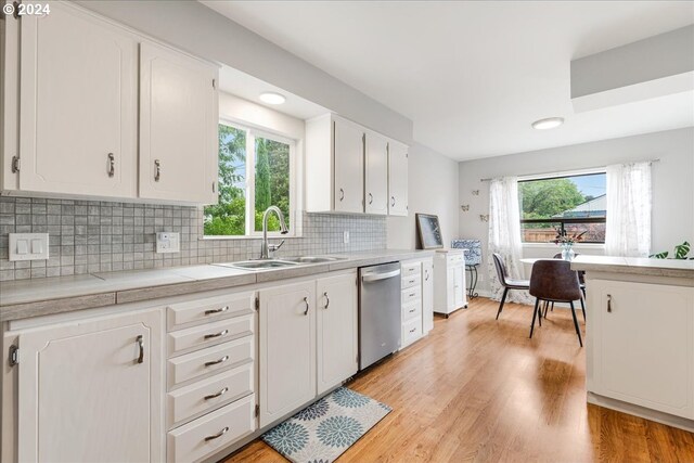 kitchen featuring stainless steel dishwasher, white cabinets, sink, and tasteful backsplash