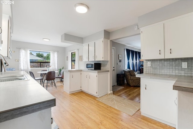 kitchen featuring white cabinets, tasteful backsplash, light hardwood / wood-style floors, and sink