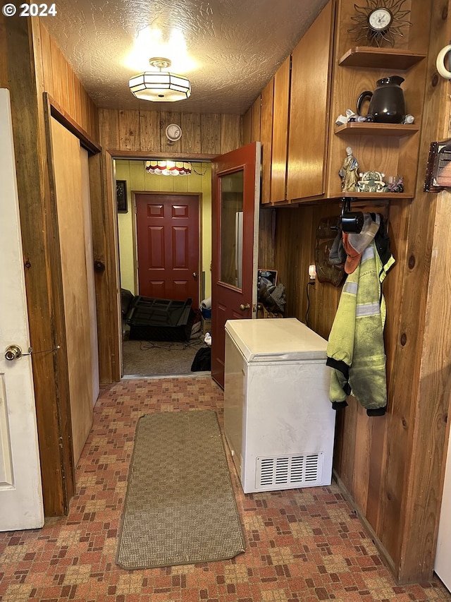 washroom with wood walls and a textured ceiling