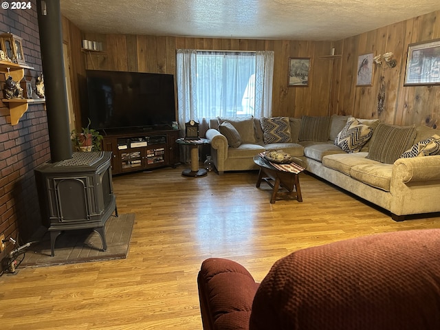 136350 Main St, Crescent, OR 97733 - living room featuring a wood stove, wood walls, a textured ceiling, and light wood-type flooring