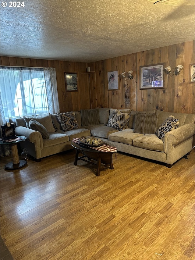 living room with wood walls, light wood-type flooring, and a textured ceiling