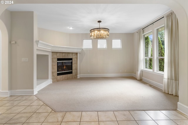 unfurnished living room featuring light colored carpet, a notable chandelier, and a fireplace