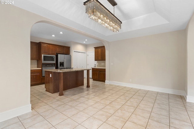 kitchen featuring pendant lighting, light tile patterned floors, backsplash, stainless steel appliances, and a center island