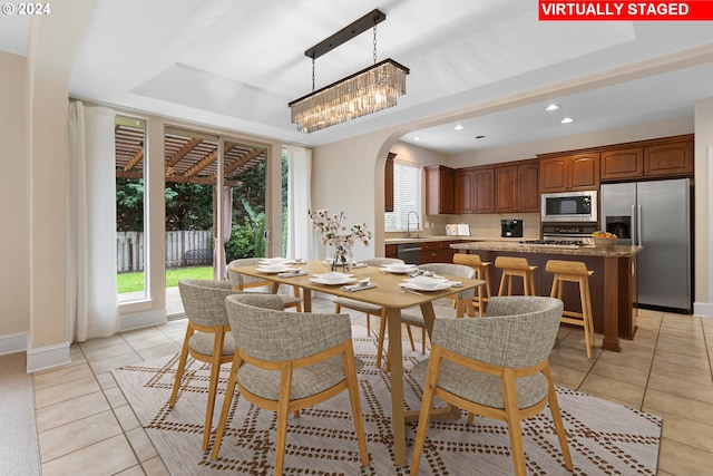 dining area featuring a raised ceiling, sink, and light tile patterned floors