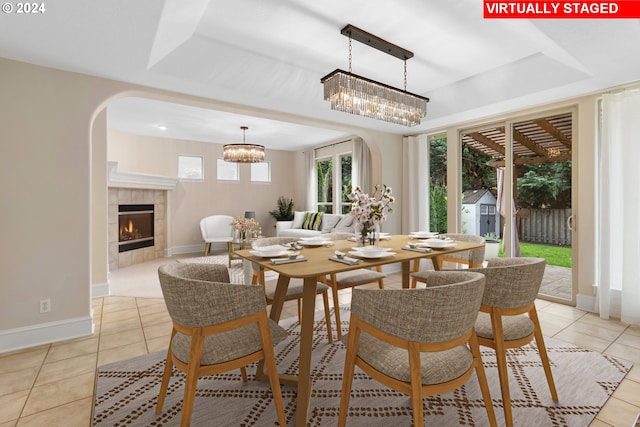 tiled dining room featuring a fireplace and a tray ceiling