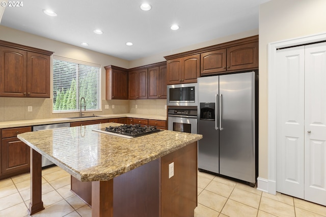 kitchen with light tile patterned flooring, sink, light stone counters, appliances with stainless steel finishes, and a kitchen island