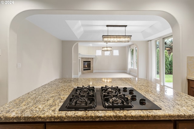 kitchen featuring light stone counters, a tray ceiling, and black gas cooktop