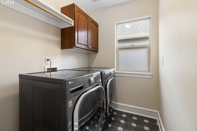 clothes washing area with cabinets and washing machine and dryer