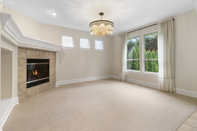 unfurnished living room featuring light colored carpet, a tiled fireplace, and a notable chandelier