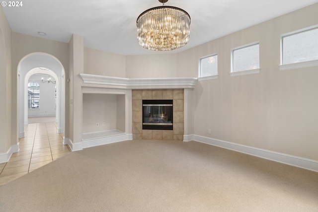 unfurnished living room with a healthy amount of sunlight, light carpet, and a chandelier