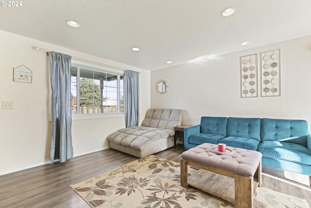 living room with a textured ceiling, wood walls, and dark hardwood / wood-style floors