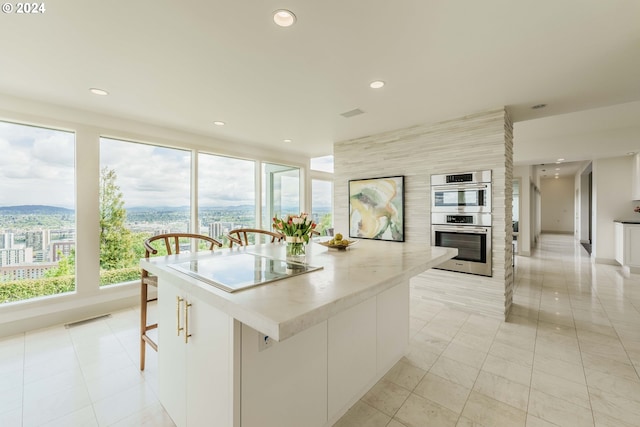 kitchen with a mountain view, a center island, white cabinets, light tile patterned floors, and double oven