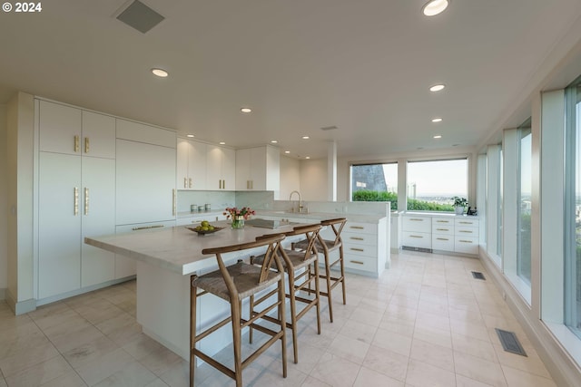 kitchen featuring white cabinetry, sink, tasteful backsplash, a kitchen breakfast bar, and kitchen peninsula