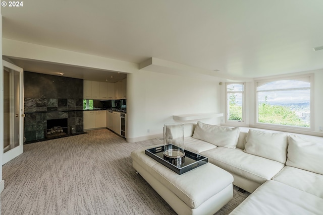 living room with a tile fireplace and light carpet