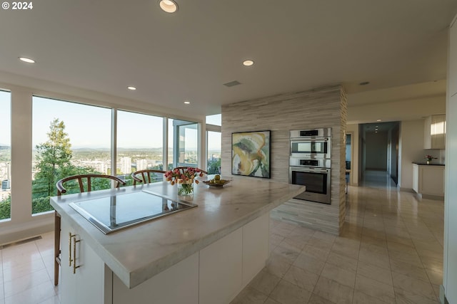 kitchen with a center island, white cabinetry, light tile patterned floors, stovetop, and stainless steel double oven