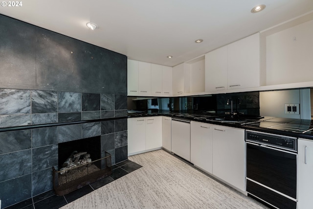 kitchen featuring a tile fireplace, white cabinetry, sink, and light tile patterned floors