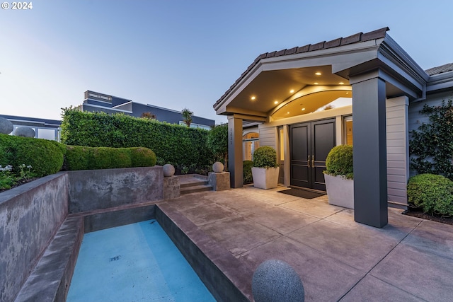 pool at dusk with a patio area