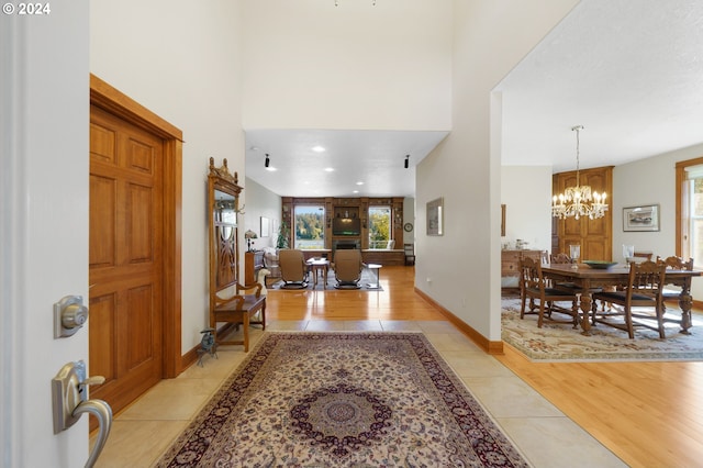 foyer entrance with light hardwood / wood-style flooring, a towering ceiling, and a chandelier