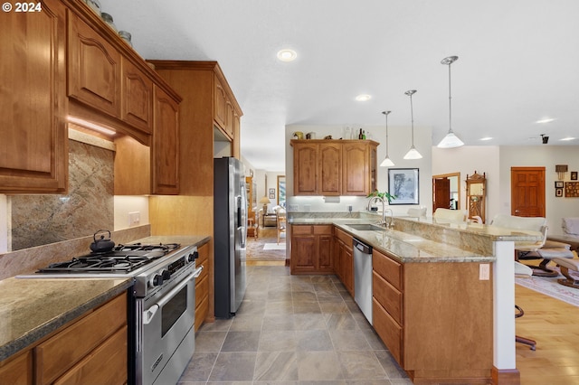 kitchen with appliances with stainless steel finishes, a breakfast bar, kitchen peninsula, pendant lighting, and sink