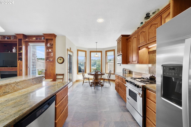 kitchen with hanging light fixtures, stone countertops, and stainless steel appliances