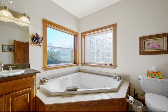 bathroom featuring vanity, a relaxing tiled tub, and toilet