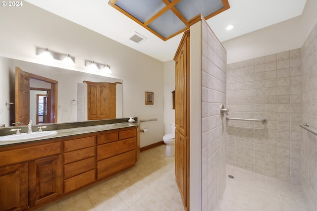 bathroom featuring a tile shower, tile patterned flooring, vanity, and toilet