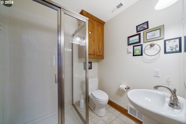 bathroom featuring tile patterned flooring, a shower with shower door, and toilet