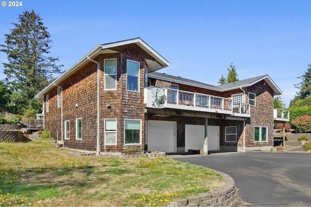 rear view of property featuring a balcony and a garage