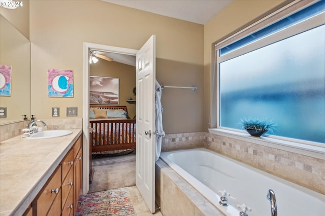 bathroom with vanity, lofted ceiling, a wealth of natural light, and tiled bath