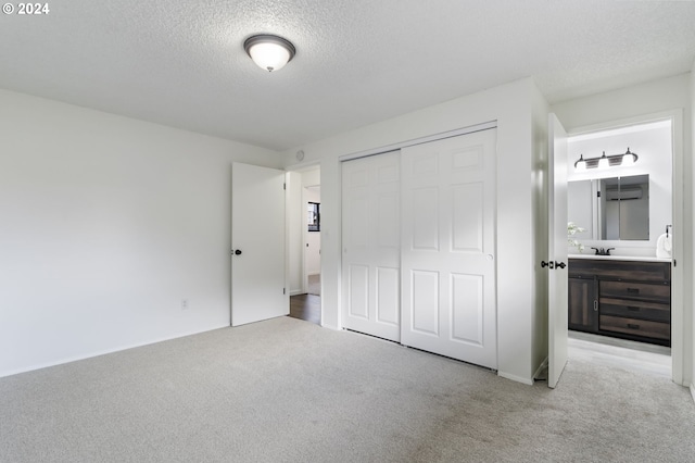 unfurnished bedroom featuring a textured ceiling, connected bathroom, light colored carpet, and a closet