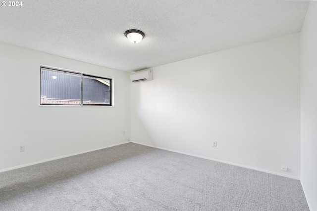 unfurnished room featuring an AC wall unit, carpet floors, and a textured ceiling