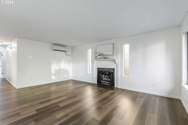 unfurnished living room featuring a textured ceiling, dark wood-type flooring, and a wall mounted air conditioner