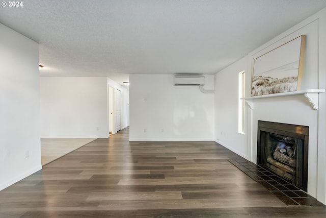 unfurnished living room featuring a textured ceiling, dark hardwood / wood-style flooring, and a wall unit AC