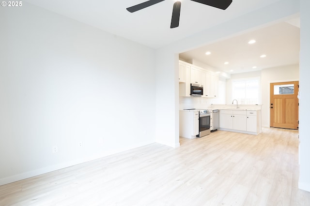 kitchen with appliances with stainless steel finishes, ceiling fan, sink, light hardwood / wood-style floors, and white cabinetry