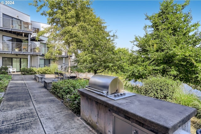 exterior space featuring a balcony, area for grilling, and exterior kitchen