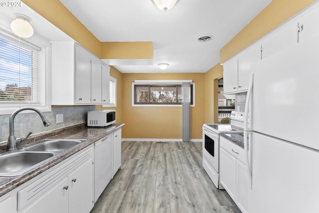 kitchen with white appliances, backsplash, white cabinets, sink, and light hardwood / wood-style flooring