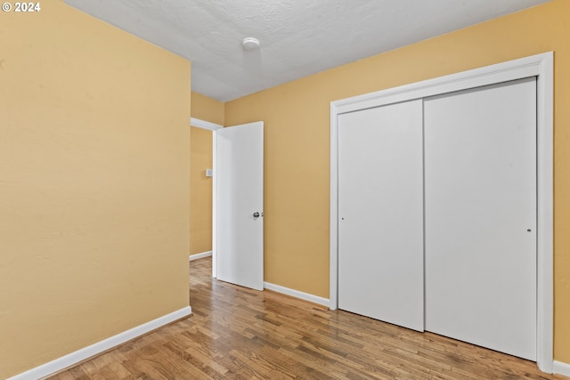 unfurnished bedroom featuring hardwood / wood-style floors, a textured ceiling, and a closet