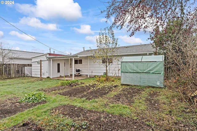 rear view of property featuring a patio area, an outdoor structure, and a lawn