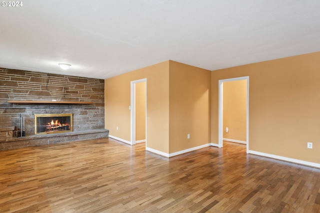 unfurnished living room with a stone fireplace and wood-type flooring