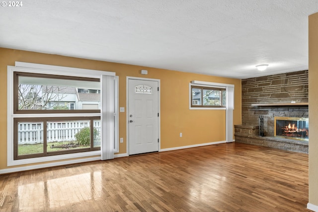 unfurnished living room with a fireplace, hardwood / wood-style floors, and a textured ceiling