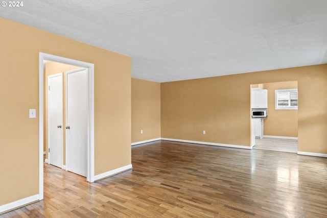 unfurnished room with hardwood / wood-style floors and a textured ceiling