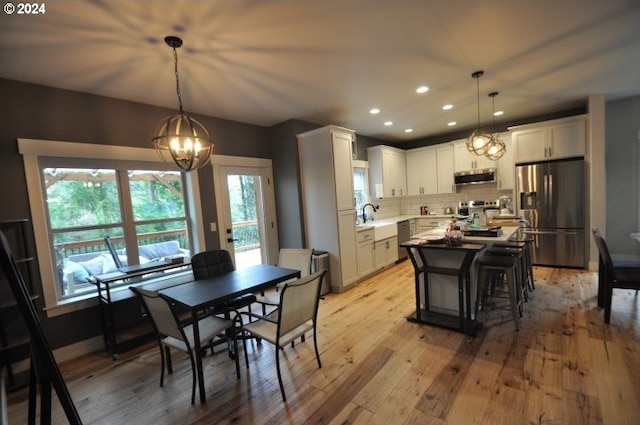 kitchen with light hardwood / wood-style flooring, decorative backsplash, decorative light fixtures, white cabinetry, and stainless steel appliances