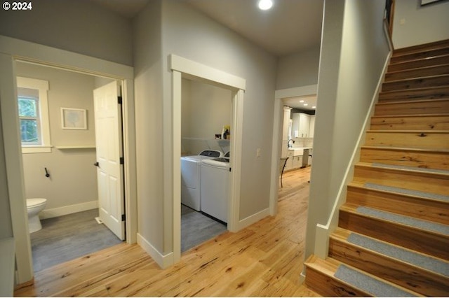 interior space featuring washing machine and clothes dryer and light hardwood / wood-style flooring