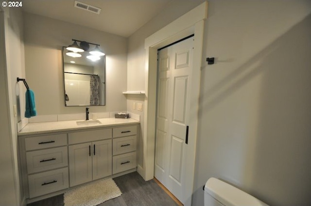 bathroom featuring hardwood / wood-style floors, vanity, curtained shower, and toilet