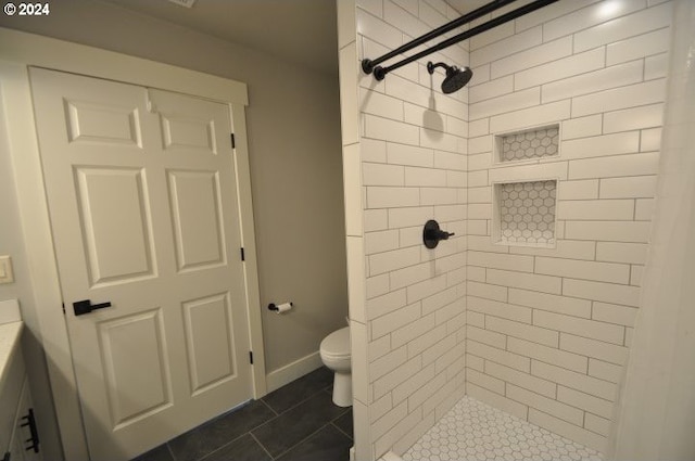 bathroom with tiled shower, tile patterned flooring, and toilet