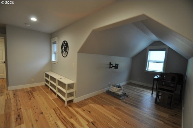 bonus room with light wood-type flooring and vaulted ceiling