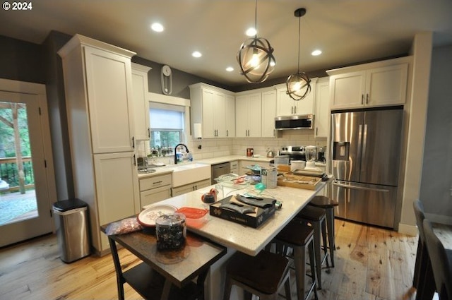 kitchen featuring plenty of natural light, a kitchen island, light hardwood / wood-style flooring, and appliances with stainless steel finishes